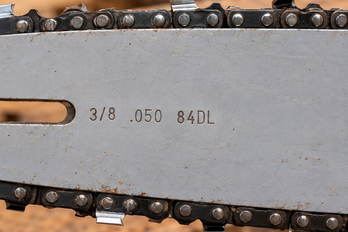 Chainsaw guide bar near its mounting slot, stamped 3/8 .050 84DL for pitch, gauge and drive link count