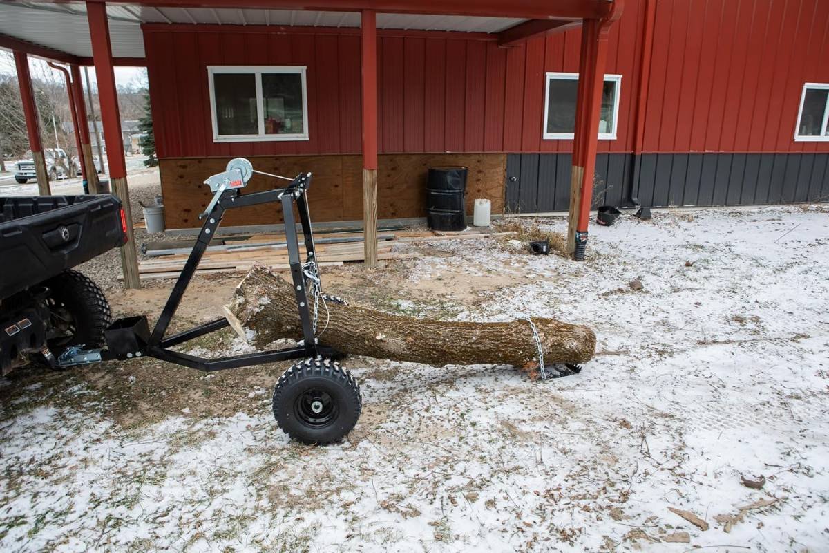 Impact Implements log hauler arch carrying a log behind a UTV in light snow