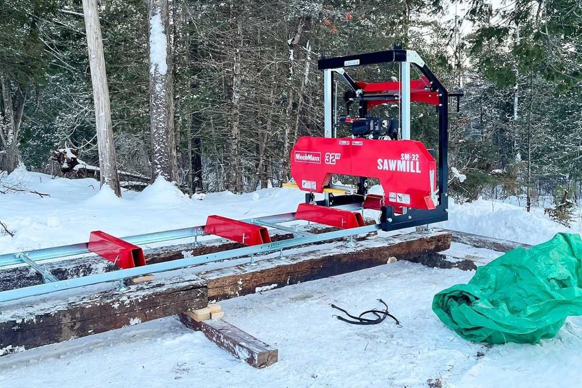 MechMaxx SM-32 portable sawmill set up on its track in a snowy yard