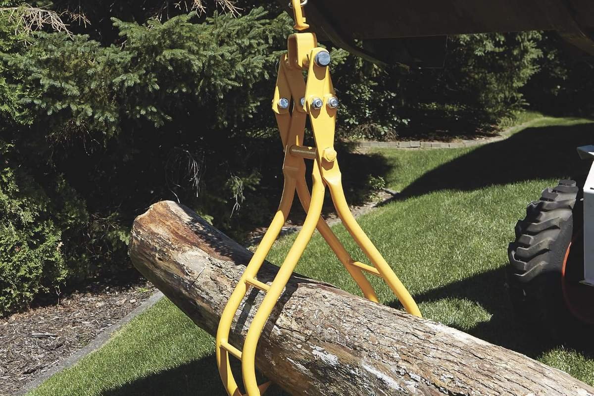 Roughneck lifting tongs on a chain gripping a log on grass