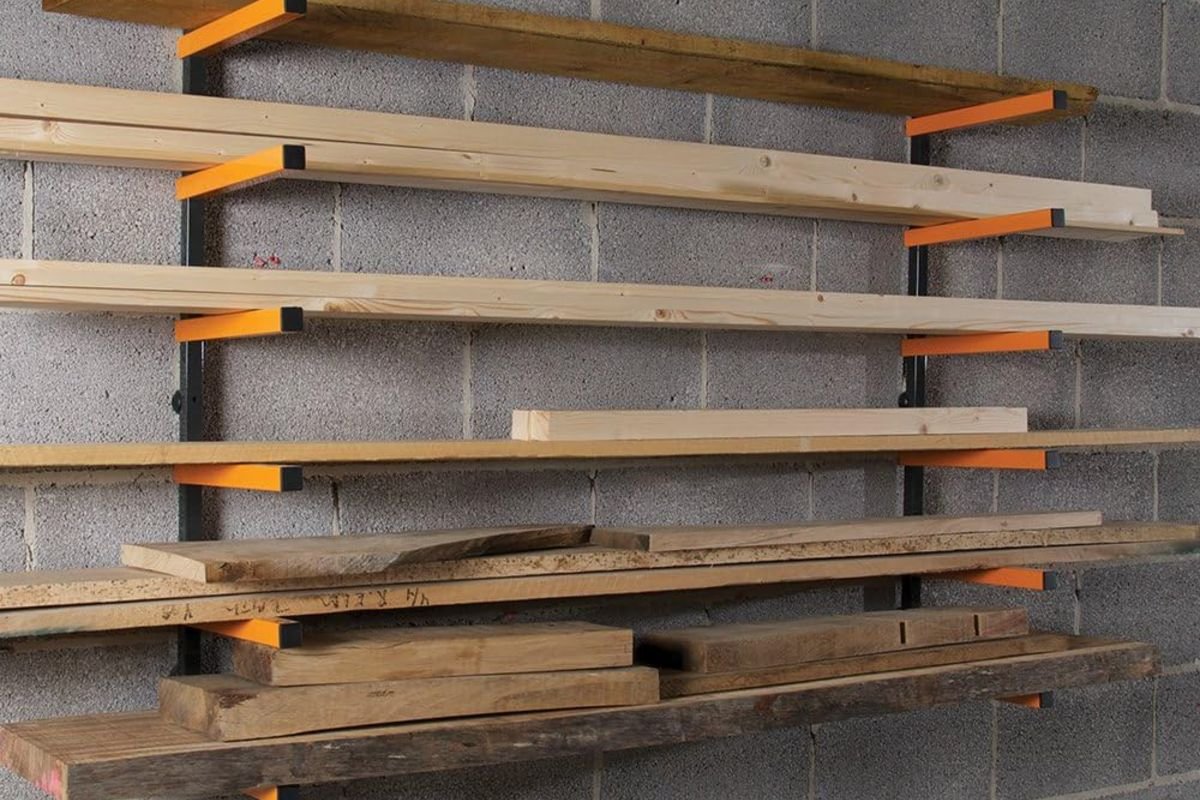 Triton WoodRack arms mounted on a block wall holding lumber