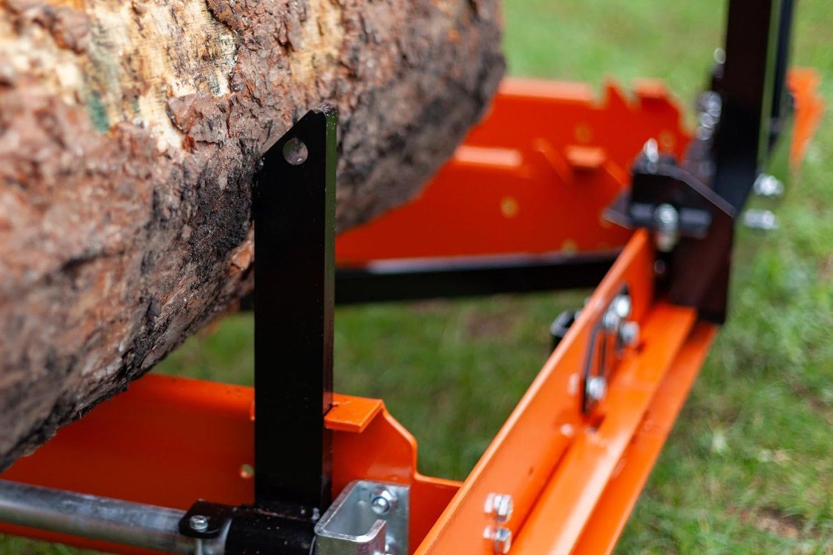 Log clamped on the bed of a Wood-Mizer LX50 sawmill on grass